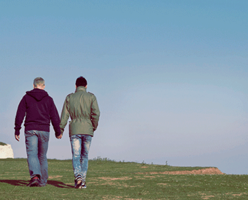 Two men walking hand in hand on a bluff
